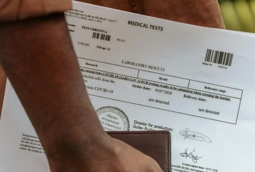 Close-up shot of a person's hand holding medical test documents and a wallet.
